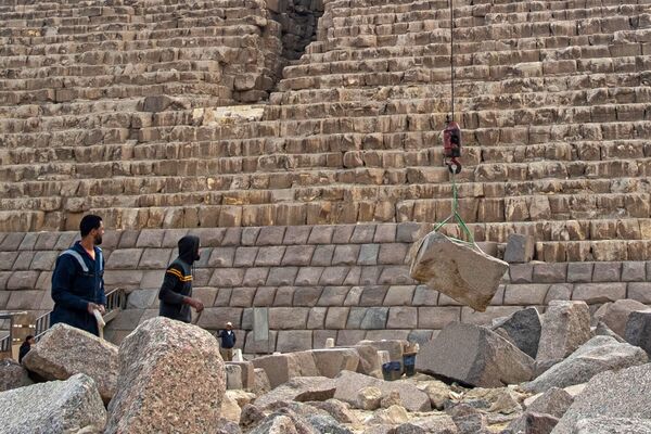 عمال يشاهدون رفع الحجارة بواسطة رافعة خلال المشروع عند قاعدة هرم &quot;منقرع&quot; - سبوتنيك عربي