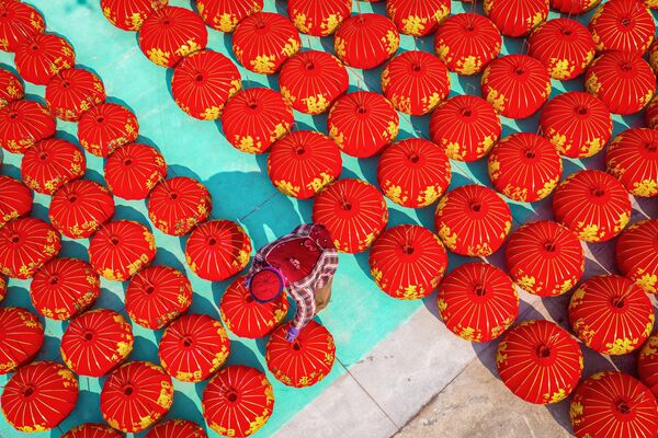 تُظهر الصورة الملتقطة في 28 يناير 2024 عاملاً ينتج فوانيس حمراء لاحتفالات العام القمري الجديد في هوايان في مقاطعة جيانغسو شرقي الصين. - سبوتنيك عربي