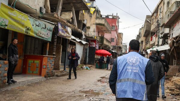 رجل يرتدي سترة تحمل شعار وكالة الأمم المتحدة لإغاثة وتشغيل اللاجئين الفلسطينيين (الأونروا) في غزة - سبوتنيك عربي