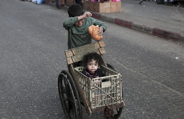 صبي يدفع طفلاً في عربة في رفح، جنوبي قطاع غزة. - سبوتنيك عربي