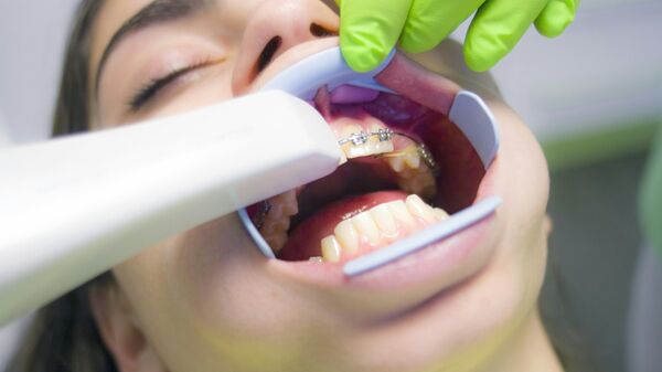 طبيب يعاين جهاز تقوم أسنان بعد تركيبه لمريضة  - سبوتنيك عربي