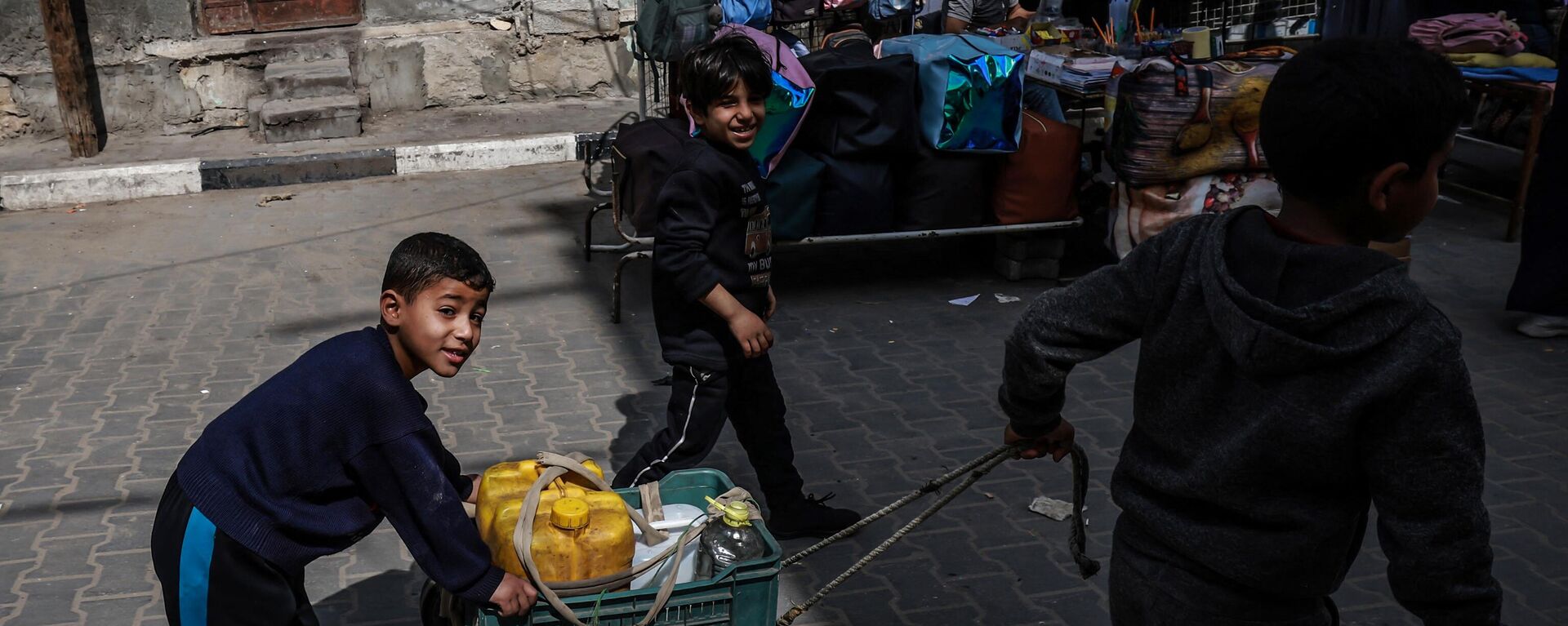 أطفال غزة -أطفال فلسطينيون نازحون يدفعون عربة محملة بصفائح المياه التي جمعوها باتجاه مخيمهم المؤقت بجانب أحد شوارع رفح، قطاع غزة، فلسطين، في 14 مارس 2024 - سبوتنيك عربي, 1920, 04.07.2024