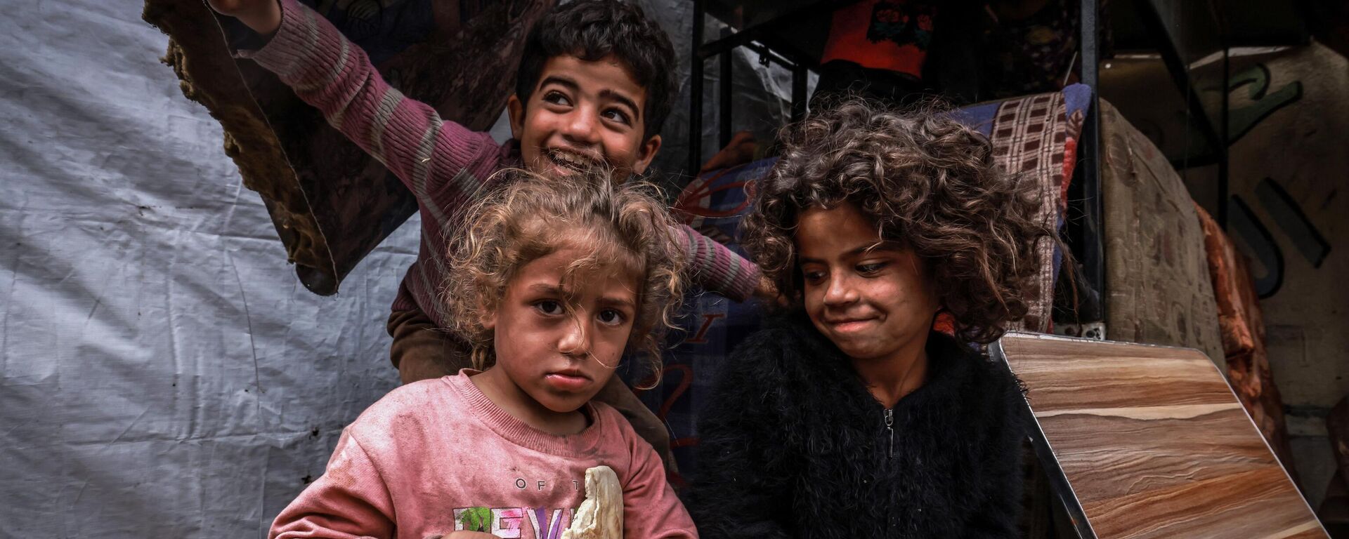أطفال غزة - أطفال فلسطينيون نازحون يلتقطون صورًا أمام خيام مؤقتة في مخيم بجانب أحد شوارع رفح، قطاع غزة، فلسطين، في 14 مارس 2024 - سبوتنيك عربي, 1920, 18.03.2024