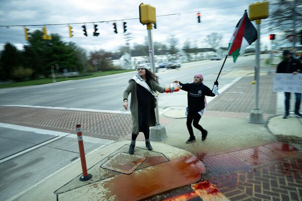 المتظاهرون الذين يحملون العلم الفلسطيني يسكبون ما يبدو أنه دماء مزيفة أثناء مرور الرئيس الأمريكي جو بايدن في طريق عودته من قداس يوم السبت في القديس يوسف في كنيسة برانديواين الكاثوليكية، 6 أبريل 2024. - سبوتنيك عربي