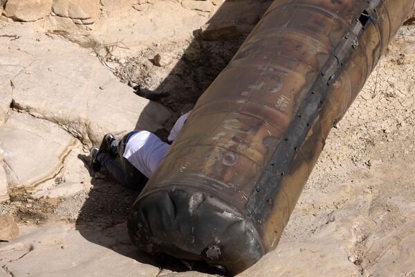 أفراد عسكريون إسرائيليون يرتدون ملابس مدنية يفحصون جزءًا من صاروخ باليستي إيراني، تم العثور عليه مؤخرًا في منطقة مفتوحة بالقرب من مدينة عراد الجنوبية. - سبوتنيك عربي