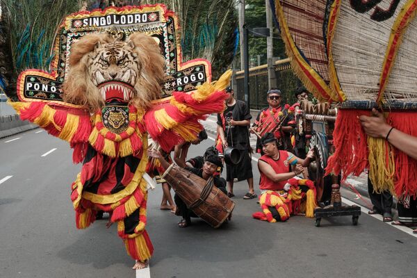 راقصون يؤدون رقصة ريوغ الإندونيسية التقليدية على طريق مغلق خلال مسيرة نظمت للاحتفال بيوم العمال العالمي في جاكرتا في 1 مايو 2024. - سبوتنيك عربي