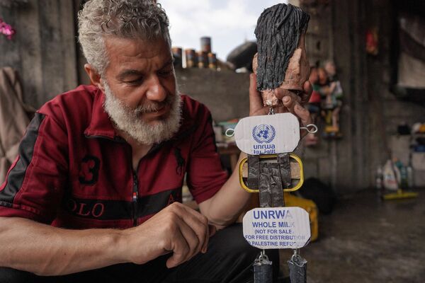 الفلسطيني مهدي كريرة يعرض إحدى دمياته المصنوعة من علب مصفحة في ورشته في دير البلح وسط قطاع غزة، 27 أبريل 2024 - سبوتنيك عربي