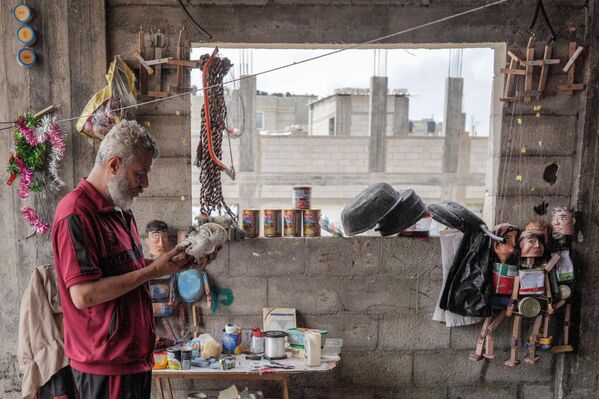 الفلسطيني مهدي كريرة يعمل على إحدى دمياته المصنوعة من علب المعلبات في ورشته في دير البلح وسط قطاع غزة، 27 أبريل 2024 - سبوتنيك عربي