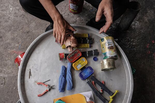 الفلسطيني مهدي كريرة يعرض إحدى دمياته، المصنوعة من علب المعلبات القديمة، في ورشته في دير البلح وسط قطاع غزة، في 27 أبريل 2024 - سبوتنيك عربي
