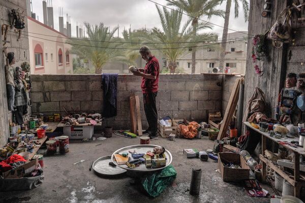 الفلسطيني مهدي كريرة يعمل على دمية مصنوعة من علب المعلبات القديمة في ورشته في دير البلح وسط قطاع غزة، في 27 أبريل 2024 - سبوتنيك عربي