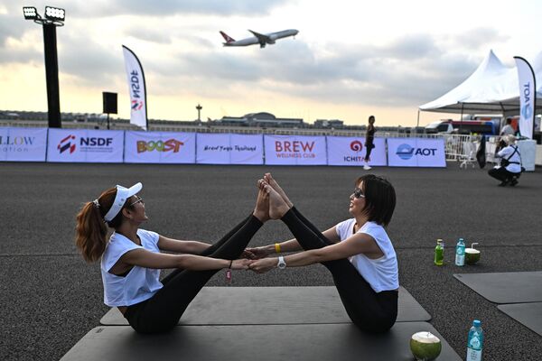 عشاق اليوغا يؤدون اليوغا أثناء حدث &quot;Brew Yoga&quot; عند شروق الشمس على المدرج بينما تقلع طائرة من مطار سوفارنابومي في بانكوك في 27 أبريل 2024. - سبوتنيك عربي