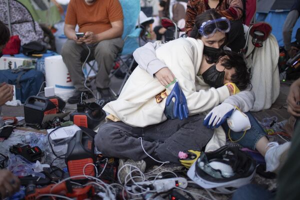 متظاهرون مؤيدون للفلسطينيين يتعانقون أثناء شحن الأجهزة في معسكر بحرم جامعة كاليفورنيا. - سبوتنيك عربي