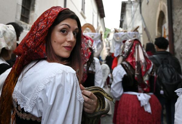 امرأة تحمل ثعبانا أثناء موكب القديس دومينيك في قرية كوكولو بوسط إيطاليا، في الأول من مايو 2024، كجزء من المهرجان التقليدي لـ &quot;Serpari&quot; (صائدي الثعابين). - سبوتنيك عربي