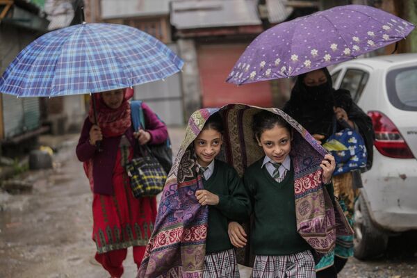 أطفال المدارس العائدون إلى منازلهم يغطون رؤوسهم أثناء هطول الأمطار في سريناجار، كشمير الخاضعة للسيطرة الهندية، الاثنين 29 أبريل 2024. - سبوتنيك عربي