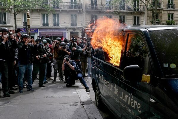 مصورون يلتقطون صوراً لشاحنة مشتعلة على هامش الاحتجاج السنوي بمناسبة يوم العمال العالمي في باريس في 1 مايو 2024. - سبوتنيك عربي