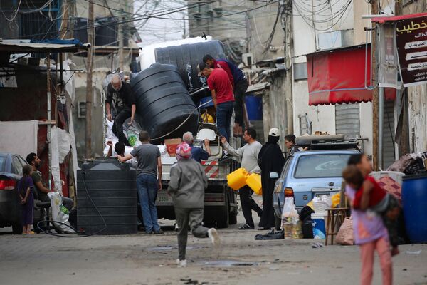 فلسطينيون يقومون بتحميل حاويات المياه على ظهر شاحنة أثناء نزوحهم من رفح جنوبي قطاع غزة، 11 مايو 2023 - سبوتنيك عربي