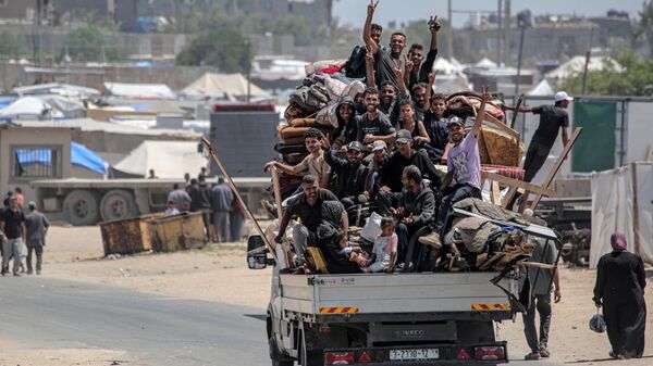 Палестинцы, бежавшие из Рафаха на юге сектора Газа, едут со своими вещами в кузове грузовика, чтобы укрыться в Дейр-эль-Балахе в центральной части палестинской территории - سبوتنيك عربي