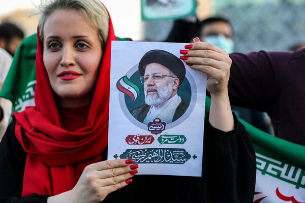 امرأة تحمل صورة للرئيس الإيراني المنتخب حديثا إبراهيم رئيسي بينما يحتفل أنصاره بفوزه في ساحة الإمام الحسين بالعاصمة طهران في 19 يونيو 2021. - سبوتنيك عربي