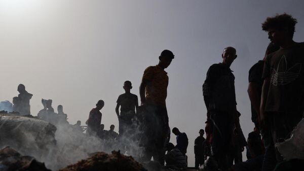 فلسطينيون يتجمعون في موقع غارة إسرائيلية على مخيم للنازحين في رفح، 27 مايو/ أيار 2024 - سبوتنيك عربي