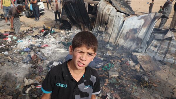 فلسطينيون يتجمعون في موقع غارة إسرائيلية على مخيم للنازحين في رفح في 27 مايو، 2024 - سبوتنيك عربي