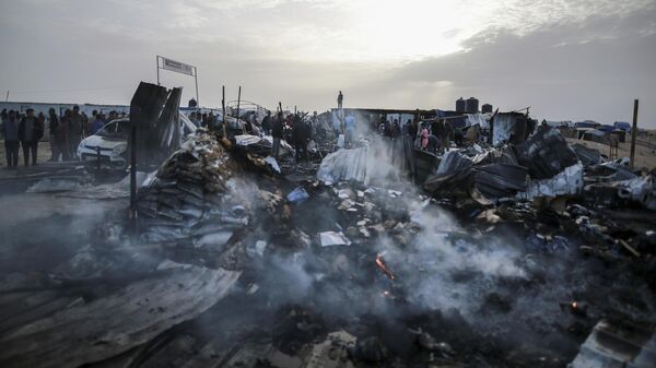 فلسطينيون ينظرون إلى الدمار بعد غارة إسرائيلية على مكان إقامة النازحين في رفح، قطاع غزة، الاثنين 27 مايو 2024 - سبوتنيك عربي