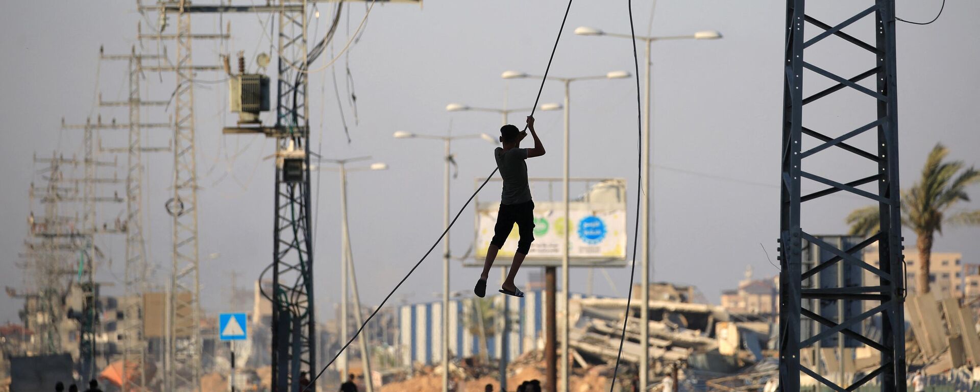 شباب فلسطينيون يتأرجحون على كابلات الكهرباء المعلقة في مخيم المغازي للاجئين في وسط قطاع غزة في 5 يونيو/ حزيران 2024 - سبوتنيك عربي, 1920, 10.06.2024