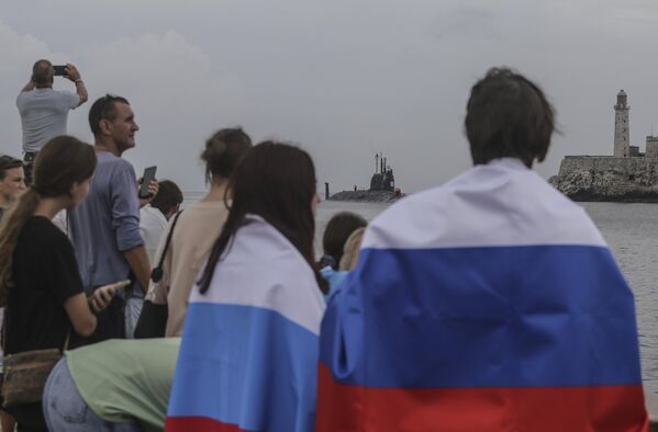 أشخاص يرتدون الأعلام الروسية يشاهدون غواصة &quot;قازان&quot; الروسية التي تعمل بالطاقة النووية تصل إلى ميناء هافانا، كوبا، الأربعاء 12 يونيو/حزيران 2024 - سبوتنيك عربي