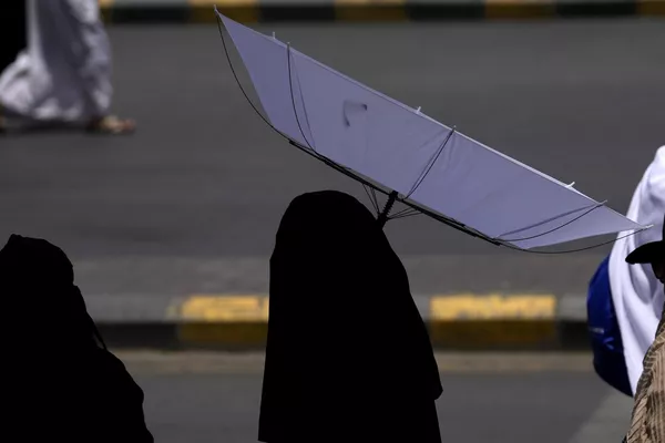 امرأة تحمل مظلة لحماية نفسها من الشمس أثناء مغادرتها بعد أداء الصلاة في الخارج في المسجد الحرام، أثناء أداء فريضة الحج السنوية في مكة، المملكة العربية السعودية، 13 يونيو 2024. - سبوتنيك عربي