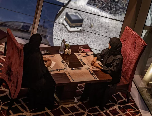 نساء يجلسن في مطعم بينما يتجول المصلون المسلمون حول الكعبة، في المسجد الحرام في مدينة مكة المكرمة بالمملكة العربية السعودية في 13 يونيو 2024، قبل أداء فريضة الحج السنوية. - سبوتنيك عربي