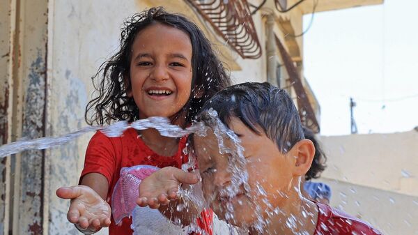 أطفال فلسطينيون يتم رشهم بالمياه وسط ارتفاع درجات الحرارة وانقطاع التيار الكهربائي في رفح بجنوب قطاع غزة، 31 يوليو/ تموز 2023 - سبوتنيك عربي