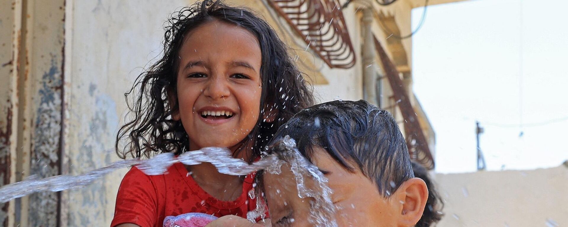 أطفال فلسطينيون يتم رشهم بالمياه وسط ارتفاع درجات الحرارة وانقطاع التيار الكهربائي في رفح بجنوب قطاع غزة، 31 يوليو/ تموز 2023 - سبوتنيك عربي, 1920, 21.06.2024