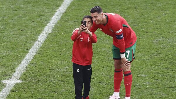 معجب صغير يلتقط صورة تذكارية مع نجم كرة القدم، كريستيانو رونالدو، خلال مباراة البرتغال وتركيا، ضمن تصفيات أمم أوروبا 2024، 22 يونيو/ حزيران 2024 - سبوتنيك عربي