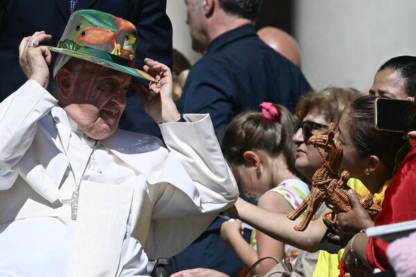 البابا فرانسيس يحاول ارتداء القبعة المقدمة له في نهاية اللقاء العام الأسبوعي، في 26 يونيو 2024، في ساحة القديس بطرس في الفاتيكان. - سبوتنيك عربي