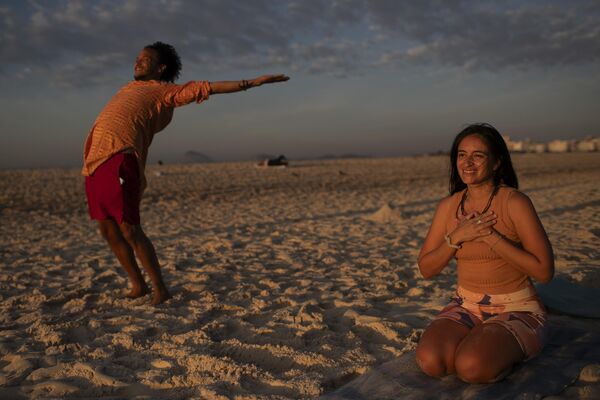 أشخاص يتمتعون ببعض أشعة الشمس خلال حدث اليوغا عند الفجر، في ريو دي جانيرو في البرازيل. - سبوتنيك عربي