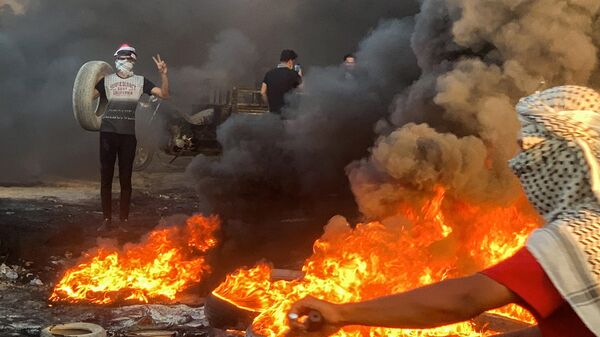 متظاهرون يحرقون إطارات لإغلاق طريق أثناء تجمعهم للاحتجاج على تدهور إمدادات الكهرباء اليومية على طريق في منطقة غماس بمحافظة الديوانية العراقية، 13 يوليو 2024 - سبوتنيك عربي