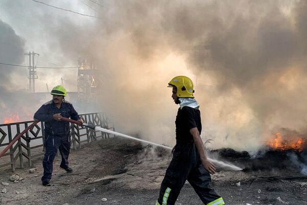 رجل إطفاء يطفئ حريق إطارات أشعله متظاهرون يحتجون على انقطاع الكهرباء ونقص المياه، وسط ارتفاع درجات الحرارة في البلاد، في قرية الشافعية على المشارف الجنوبية الغربية للديوانية، جنوب وسط العراق، في 15 يوليو 2024. - سبوتنيك عربي