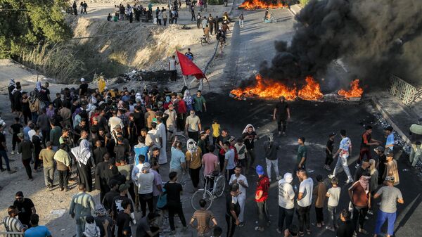 متظاهرون يتجمعون لإغلاق طريق بالإطارات المحترقة خلال احتجاج على انقطاع الكهرباء ونقص المياه خلال حرارة الصيف الشديدة، في قرية الشافعية على المشارف الجنوبية الغربية للديوانية في جنوب وسط العراق في 15 يوليو 2024 - سبوتنيك عربي