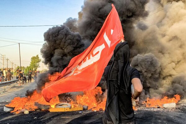 متظاهر يقف أمام الإطارات المشتعلة، خلال احتجاج على انقطاع التيار الكهربائي ونقص المياه، وسط ارتفاع درجات الحرارة في البلاد، في قرية الشافعية على المشارف الجنوبية الغربية للديوانية، جنوب وسط العراق، في 15 يوليو 2024. - سبوتنيك عربي