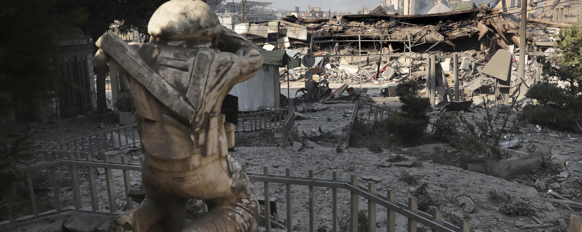 متاجر مدمرة أمام تمثال لمقاتل من حزب الله في شارع تجاري تعرض لغارات جوية إسرائيلية مساء السبت في بلدة النبطية جنوب لبنان، 13 أكتوبر 2024. - سبوتنيك عربي, 1920, 08.09.2025