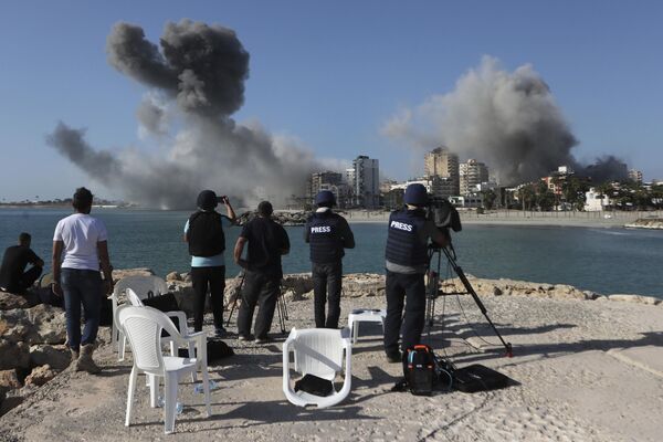 صحفيون يوثقون تصاعد الدخان من المباني التي استهدفتها الغارات الجوية الإسرائيلية في صور، جنوبي لبنان. - سبوتنيك عربي