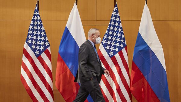 شخص يمشي أمام العلمين الروسي والأمريكي قبل المحادثات التي جرت بين نائب وزير الخارجية الروسي سيرغي ريابكوف ونائبة وزير الخارجية الأمريكي ويندي شيرمان في مقر البعثة الأمريكية في جنيف، سويسرا، 2022 - سبوتنيك عربي