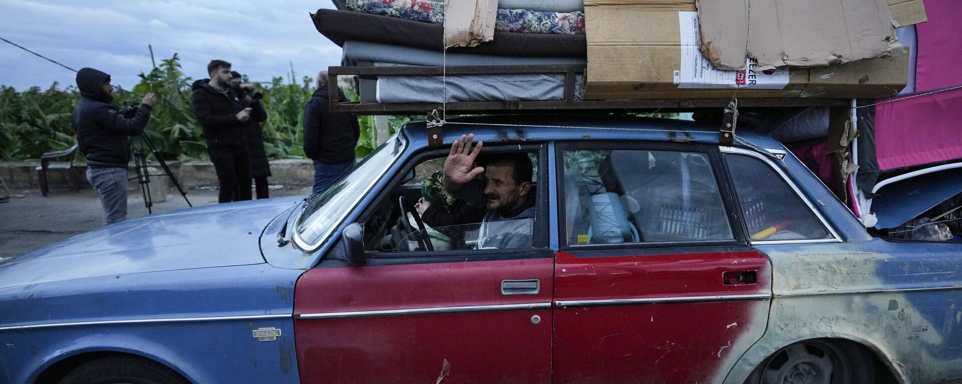 رجل عائد إلى قريته يلوح بيديه وهو يحمل أمتعته على سيارته بعد بدء وقف إطلاق النار بين حزب الله وإسرائيل في وقت مبكر من الصباح، في صور، جنوب لبنان، الأربعاء 27 نوفمبر 2024. - سبوتنيك عربي, 1920, 26.01.2025