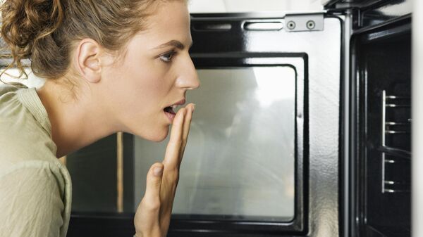 صورة لإمراة تضع طعاما في الميكرويف - سبوتنيك عربي