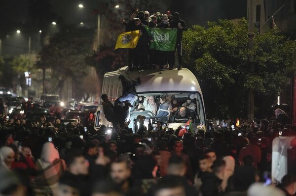 حشد من الناس يتجمعون حول حافلة تقل سجناء فلسطينيين محررين لدى وصولها إلى مدينة بيتونيا في الضفة الغربية. - سبوتنيك عربي