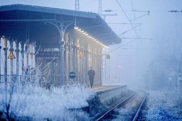 شخص يمشي على رصيف محطة القطار في أوبرورسيل بالقرب من فرانكفورت، ألمانيا ويظهر حوله تشكيلات جليدية نتيجة البرد القارس.  - سبوتنيك عربي