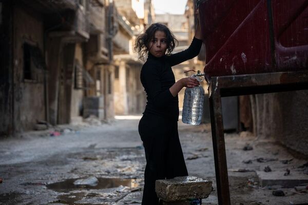 فتاة تملأ زجاجة ماء في مخيم اليرموك للاجئين الفلسطينيين في دمشق، سوريا، وهو أحد أفقر الأحياء في دمشق. - سبوتنيك عربي