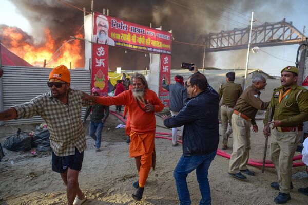 يخلي المصلون خيمتهم المحترقة بعد اندلاع حريق كبير في منطقة مهرجان ماها كومبه ميلا في الله أباد، الهند. - سبوتنيك عربي