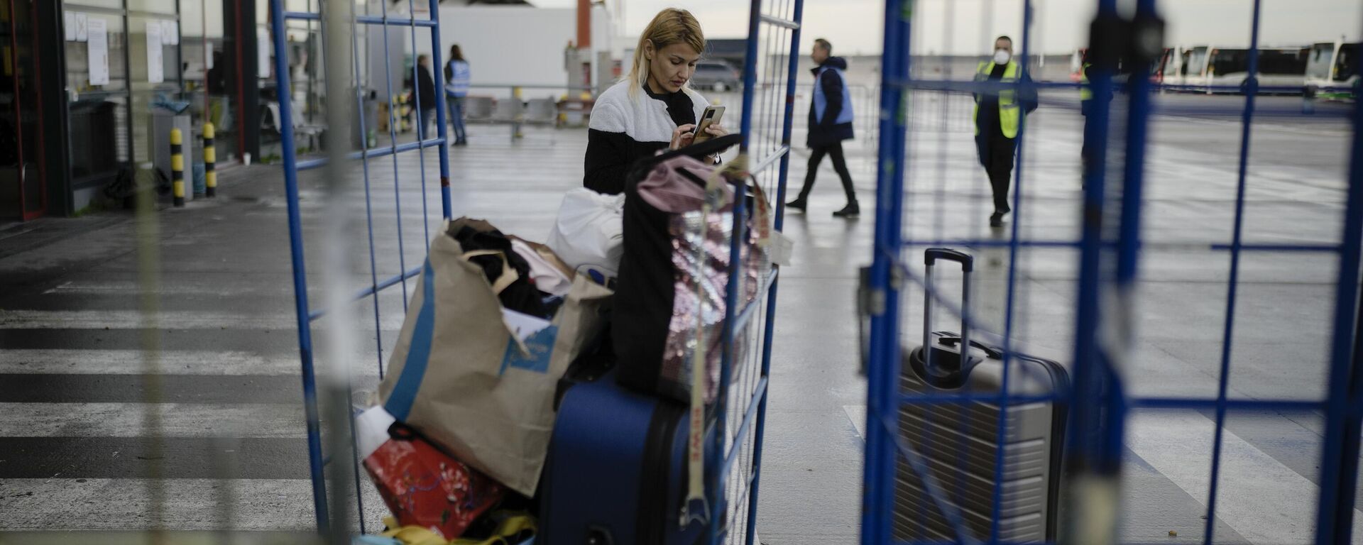 A woman from Ukraine checks her mobile as she arrives with her belongings at the temporary refugee shelter.  - سبوتنيك عربي, 1920, 25.01.2025
