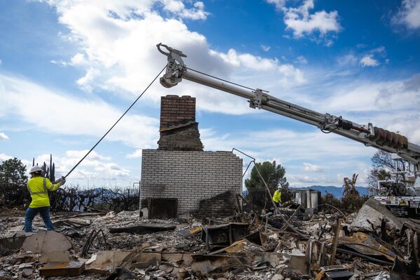 يعمل عمال الكهرباء على إعادة توصيل الكهرباء إلى المنازل الموجودة في منطقة حريق إيتون في ألتادينا وإزالة الأعمدة المحترقة - سبوتنيك عربي