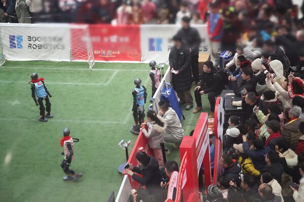 زوار يشاهدون الروبوتات خلال لعبها كرة القدم في معرض للعلوم والتكنولوجيا في بكين في الصين - سبوتنيك عربي